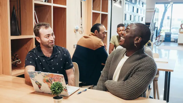 Colleagues engaging in a lively discussion at a contemporary coworking space. How to price coworking space services for a fair margin