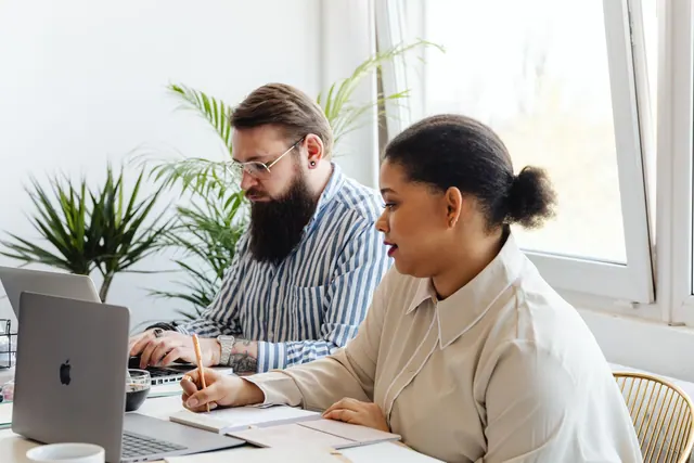 Two colleagues working together in a bright modern office space with laptops and notepads. Local SEO checklist for coworking spaces
