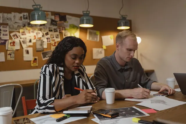Coworkers collaborating in a creative office space, working on design projects with focused attention. What licenses does a coworking space need?